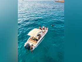 A lively group enjoys a day on the water, with some swimming and snorkeling off their boat in stunning turquoise waters — perfect for adventure seekers.