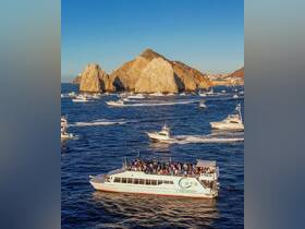 A lively group enjoys a scenic boat trip near iconic rock formations, perfect for celebrations and sightseeing in Cabo San Lucas.