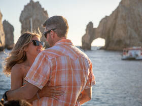 A couple shares a romantic moment against the stunning backdrop of iconic rock formations at sunset, perfect for unforgettable memories on a boat trip.