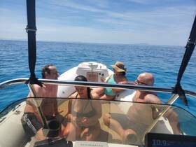 A group of friends enjoys a sunny day on the water, relaxing on a boat surrounded by beautiful blue seas — perfect for summer outings and adventures.
