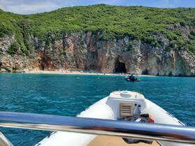 A scenic view of a boat approaching a beautiful beach with a cave, surrounded by lush greenery — a perfect destination for exploration and relaxation.