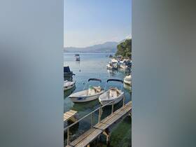 A serene view of small boats docked at a picturesque harbor, surrounded by tranquil waters and scenic mountains in the background.