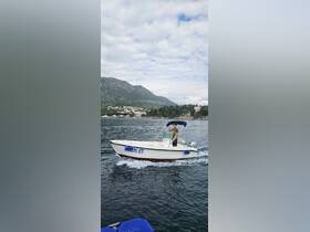 A young man navigates a speedboat through calm waters, showcasing the beautiful coastal scenery in the background — perfect for adventure seekers and boat enthusiasts.