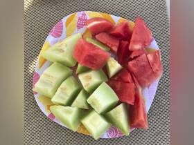 A vibrant plate of fresh watermelon and melon slices, perfect for enjoying on a boat trip or during a sunny day on the water.