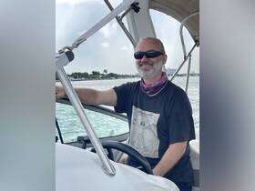 A smiling captain navigates the waters from the helm of a boat, showcasing the joy of boating adventures.