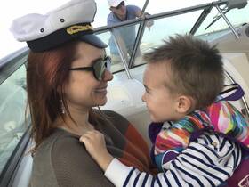 A joyful moment between a mother and her child aboard a boat, showcasing family fun and safety with a life jacket. Perfect for capturing cherished memories on the water.