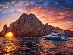 A stunning sunset view featuring a boat near a dramatic rock formation, perfect for romantic outings and scenic cruises.