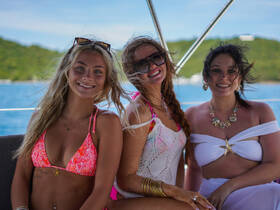 Three friends enjoy a sunny day on a boat, showcasing their vibrant swimsuits and smiles — perfect for summer adventures and celebrations on the water.