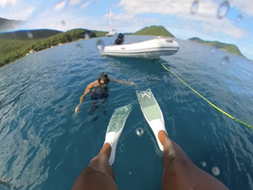 A snorkeler enjoys the vibrant underwater world while floating near a boat in crystal-clear waters — a perfect snapshot of adventure on the water.
