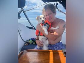 A man enjoys a sunny day on the boat with his adorable dog, both sharing a moment of joy and companionship on the water.