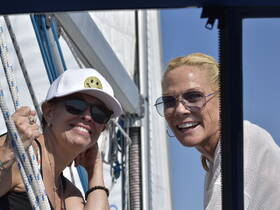 Two friends enjoy a sunny day on the boat, smiling and capturing the moment — perfect for memorable outings on the water.