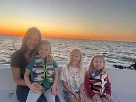 A joyful family poses together on a boat at sunset, showcasing a perfect moment of togetherness and fun on the water.