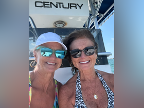 Two friends enjoy a sunny day on a Century boat, capturing a joyful moment together — perfect for memorable outings on the water.