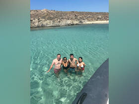 A cheerful group enjoys a refreshing swim in crystal-clear waters, capturing the essence of a perfect beach day.