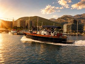 A boat navigates through the shimmering waters at sunset, showcasing a vibrant marina backdrop — perfect for evening cruises and scenic adventures.