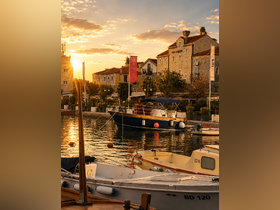 A picturesque sunset view over a tranquil harbor filled with various boats, showcasing the serene beauty of coastal life.