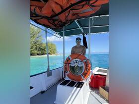 A man stands at the helm of a boat, surrounded by safety equipment and a scenic view of the turquoise waters, ideal for boat excursions.