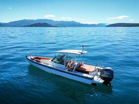 A sleek motorboat glides through clear blue waters, showcasing its elegant design against a stunning mountainous backdrop — perfect for day trips and water adventures.