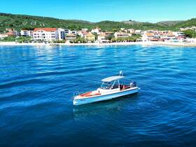 A sleek speedboat glides through clear blue waters, with a picturesque coastal town in the background, perfect for exploring the scenic coastline.