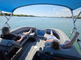 A couple relaxes on a pontoon boat, enjoying the serene waterway views — perfect for a leisurely day on the water.
