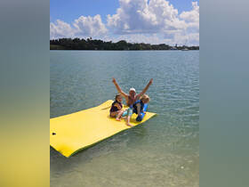 A joyful family enjoys a sunny day on a floating mat in the water, capturing the essence of fun and relaxation during their boating adventure.