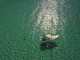 A stunning aerial view of a sailboat gliding over crystal-clear turquoise waters, showcasing the beauty of sailing adventures in tropical destinations.