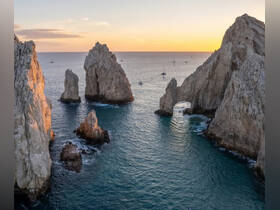 A breathtaking sunset view of the iconic rock formations at Cabo San Lucas, showcasing the stunning coastline and tranquil waters — a must-see destination for boaters and travelers.