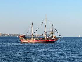 A lively pirate ship sails through the ocean, filled with guests enjoying a unique maritime experience — perfect for themed cruises and adventures on the water.