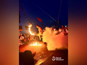 An exciting fire show captivates guests aboard a boat at night, creating a vibrant atmosphere for unforgettable celebrations and entertainment on the water.