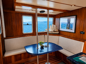 A cozy interior view of a boat's cabin featuring comfortable seating and a table, perfect for relaxing while enjoying scenic ocean views.