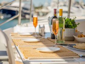 A beautifully set dining table on a yacht featuring cocktails and snacks, perfect for onboard gatherings and celebrations.