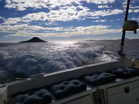 A scenic view from a boat underway, showcasing the tranquil waters and a distant island under a beautiful sky — perfect for exploring coastal destinations.