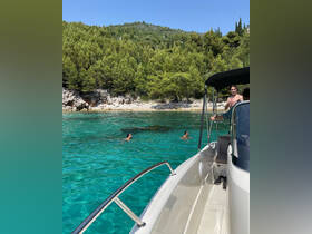 A group enjoys a refreshing swim in the crystal-clear waters while anchored near a scenic beach, showcasing the perfect summer getaway.