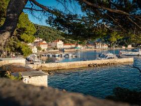 A picturesque view of a harbor with boats docked along the coastline, framed by lush greenery and charming architecture — a perfect representation of coastal beauty.