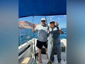 Two anglers proudly display their catch aboard a fishing boat, celebrating a successful day on the water. Perfect for fishing enthusiasts looking for adventure.