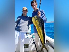 A couple proudly displays their impressive catch while fishing on the open ocean — a perfect moment of celebration and adventure.