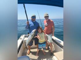 A joyful family celebrates their fishing catch aboard a boat, showcasing a memorable day on the water with smiles and excitement.