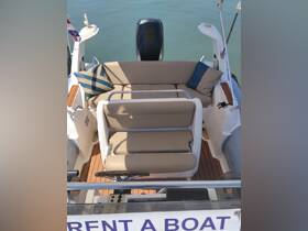 A well-appointed seating area inside a boat, featuring comfortable cushions and a helm, perfect for relaxing while cruising on the water.