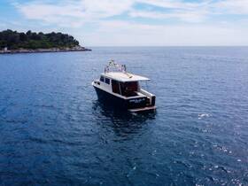 Aerial view of a sleek boat cruising through calm waters, surrounded by lush greenery — perfect for exploring coastal destinations.