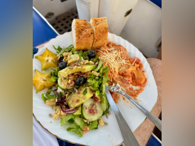 A beautifully arranged plate featuring a fresh salad, bread, and a savory dish, perfect for enjoying onboard during a relaxing day at sea.