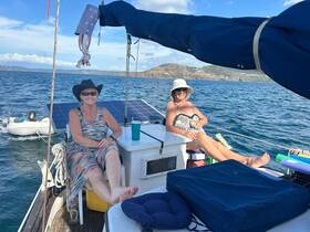 Two women relax on the deck of a boat, enjoying the sun and sea breeze — a perfect moment for leisure and camaraderie on the water.