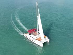 Aerial view of a sleek catamaran sailing through clear turquoise waters, showcasing its elegant design and perfect for adventurous outings.