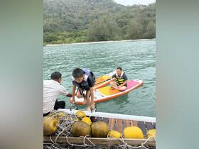A child climbs aboard while another enjoys paddleboarding in a scenic water setting, showcasing fun water activities perfect for family outings.