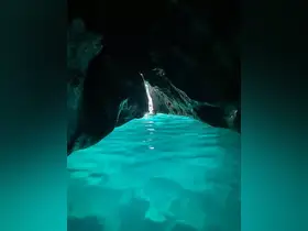 A stunning view from inside a cave, showcasing the vibrant turquoise waters and natural rock formations — a breathtaking destination for eco tours and exploration.