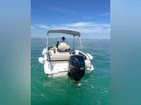 A speedboat glides through clear waters with a captain at the helm, showcasing the vessel's sleek design and functionality.