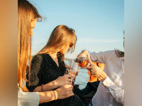 A group of friends enjoys pouring cocktails on a boat, perfect for sunset celebrations and memorable moments on the water.