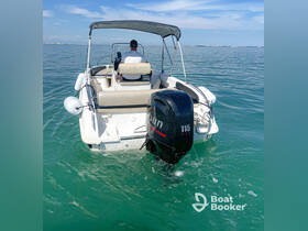 A sleek speedboat navigates through clear waters, showcasing its powerful outboard motor and comfortable seating — perfect for a day on the water.