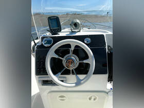 A detailed view of the helm and console of a boat, showcasing the steering wheel and navigation equipment, perfect for understanding onboard controls.