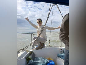 A joyful woman poses on a boat, enjoying the open water and showcasing the fun of a boating adventure.