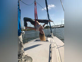 A woman performs an aerial yoga pose on the deck of a boat, showcasing a unique blend of fitness and fun on the water.